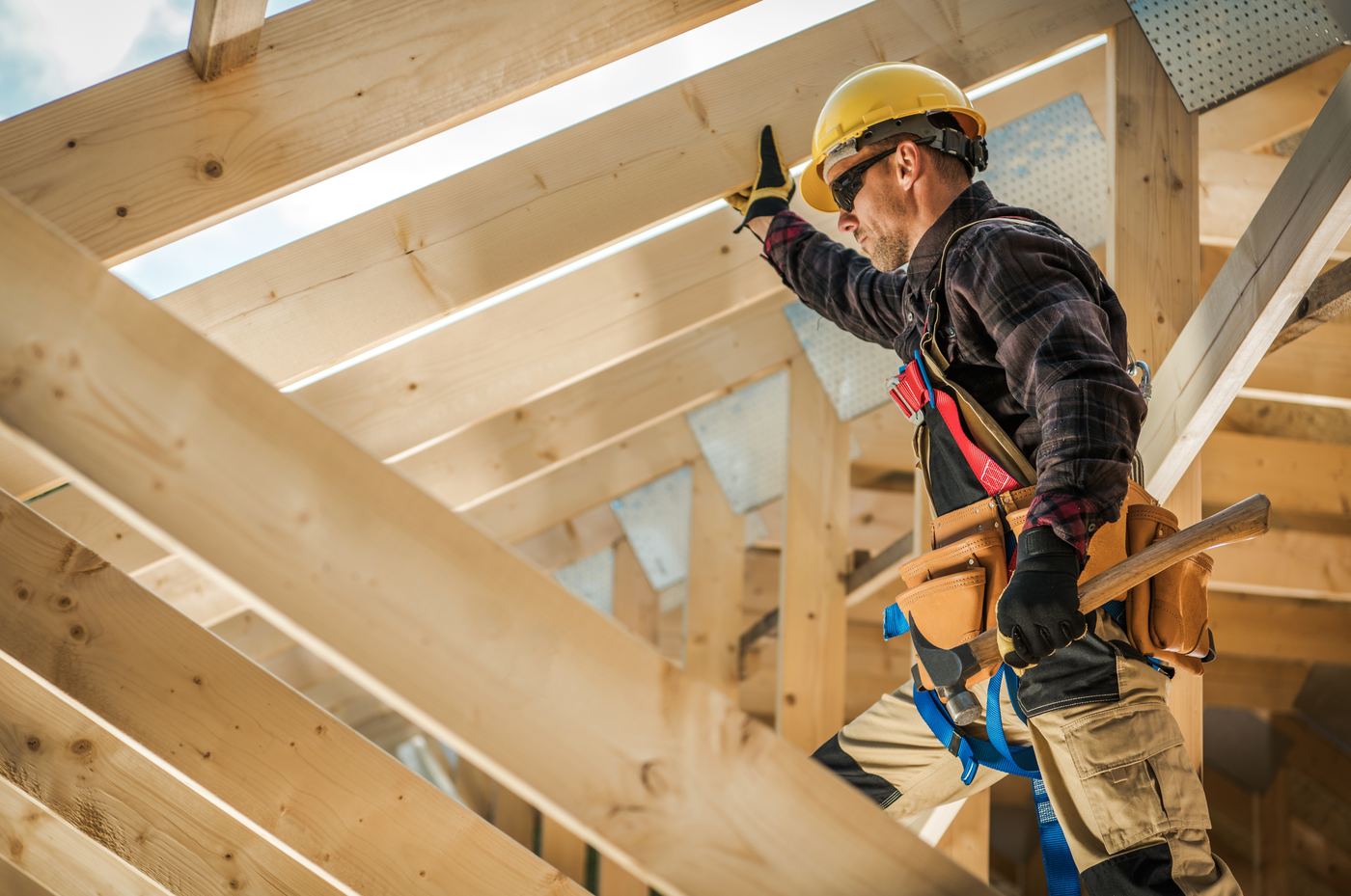 Worker in a hard hat on new wood framing, a stage where DADU building inspections take place