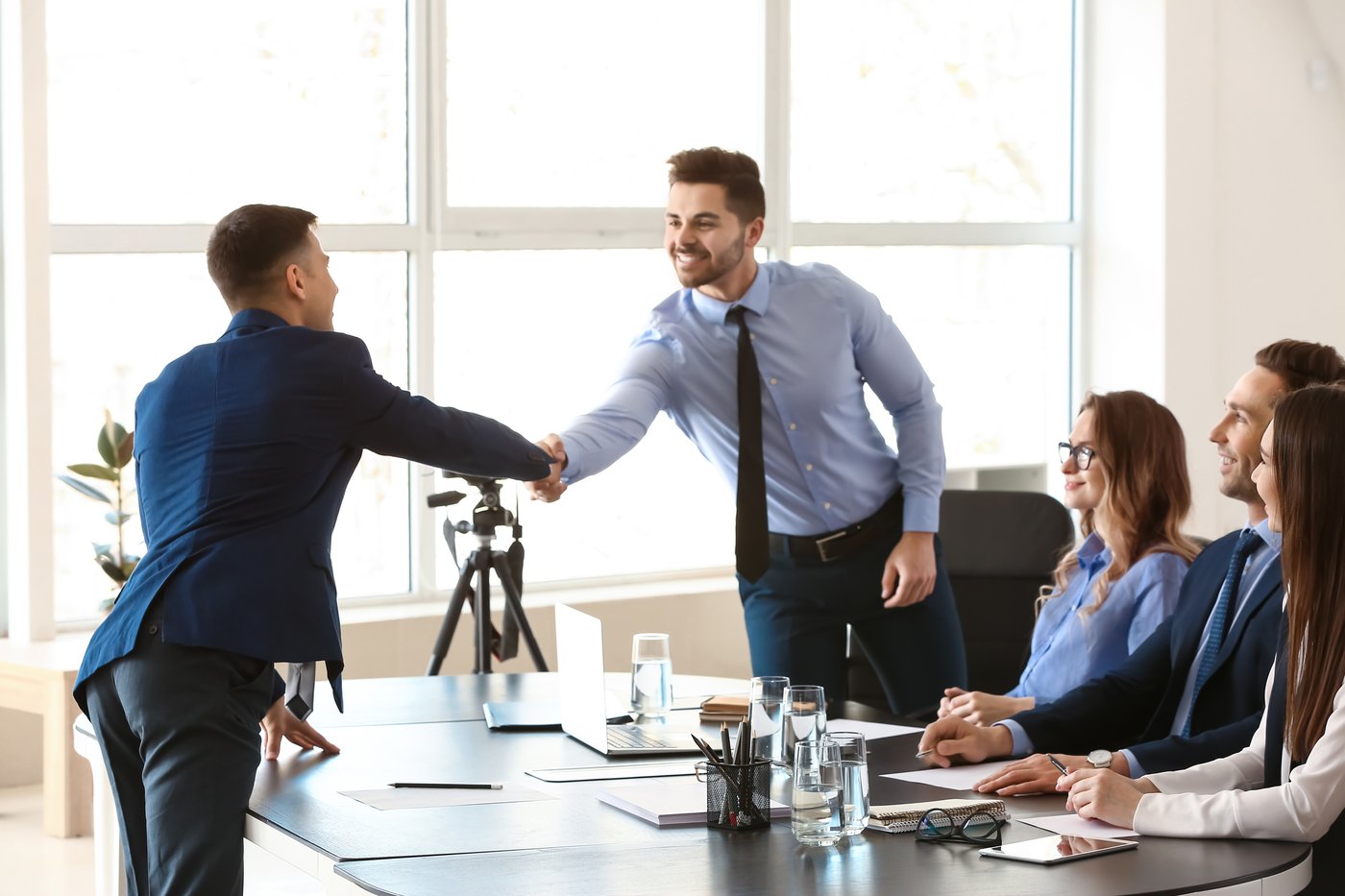 Builder shaking hands with a client at a conference table as a project team meets to discuss DADU design build options