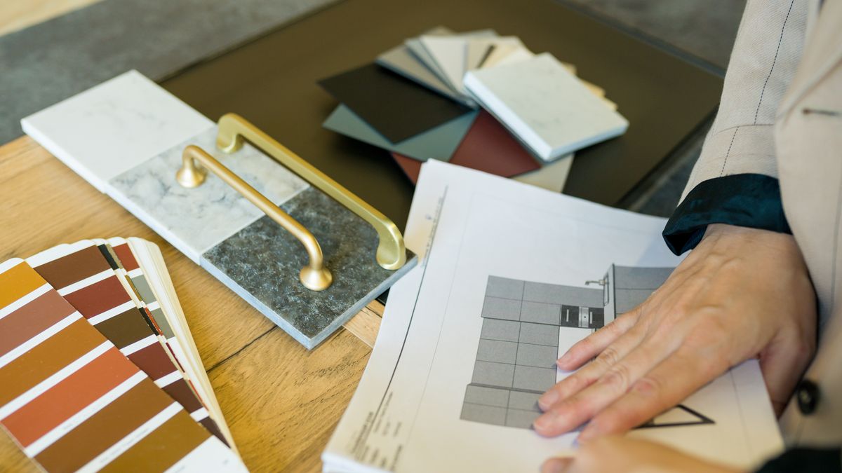 Hands sorting tile, paint swatches and cabinet hardware samples while planning DADU finish allowances