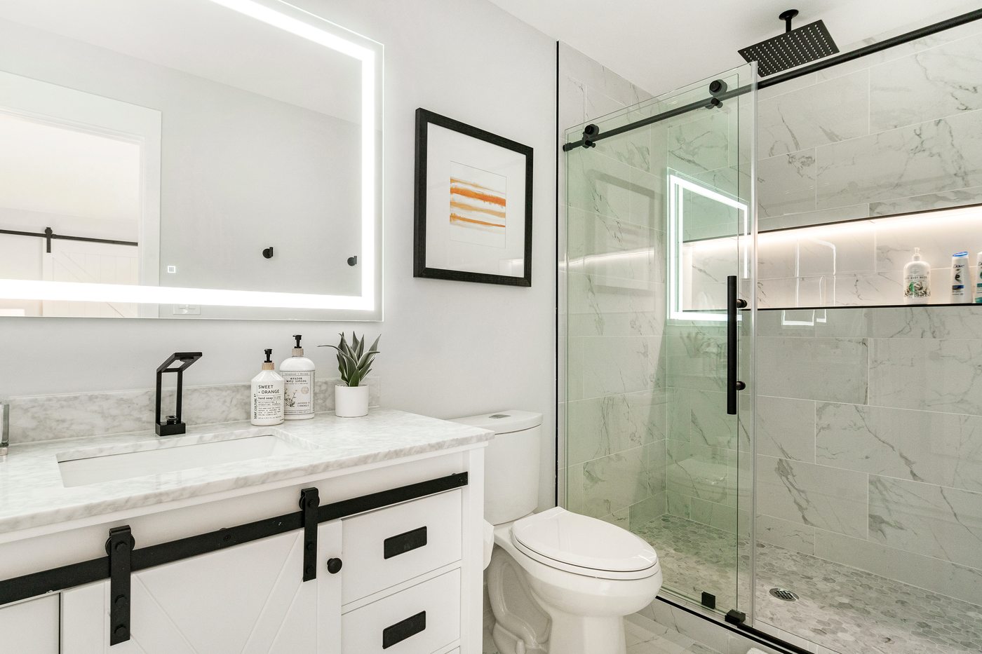 Bathroom with a white shaker vanity, quartz top, black hardware and glass tile shower