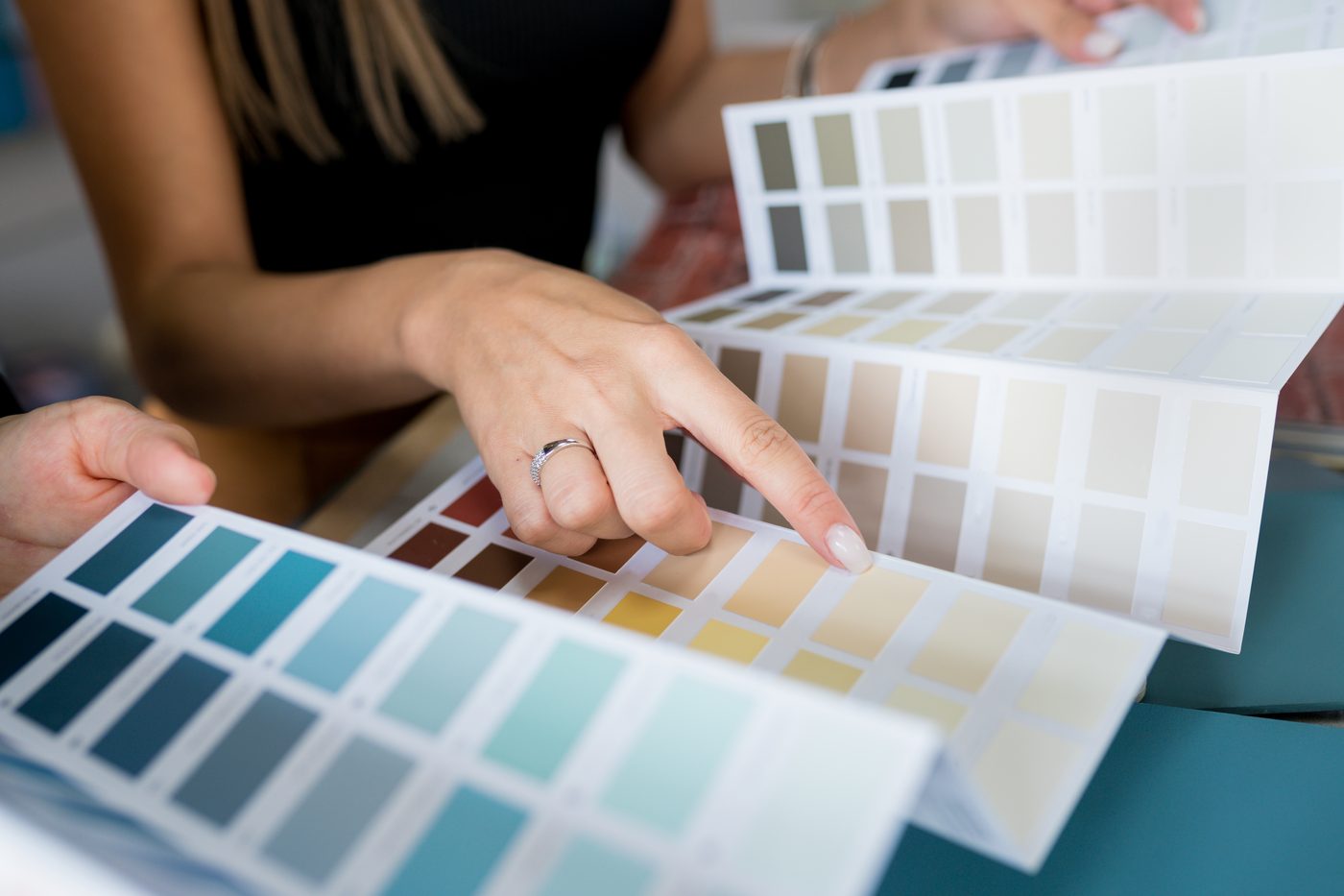 Hands comparing paint color swatch fans, the kind of early choice that helps manage DADU material lead times