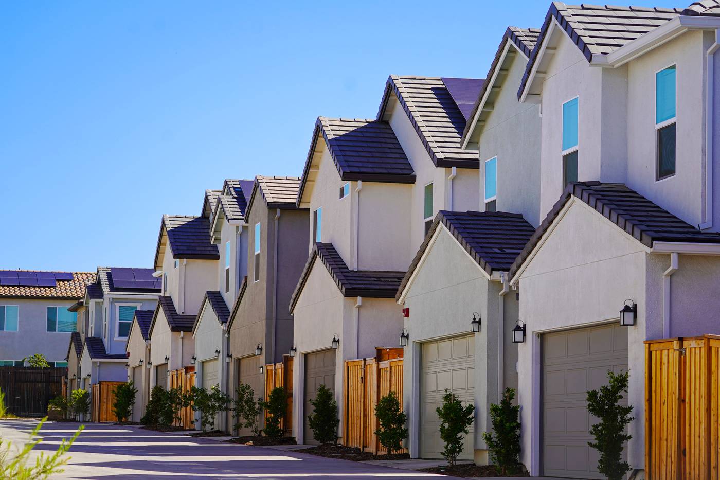 Row of attached three story townhomes with gray siding and garages, a form of housing linked to DADU separate ownership